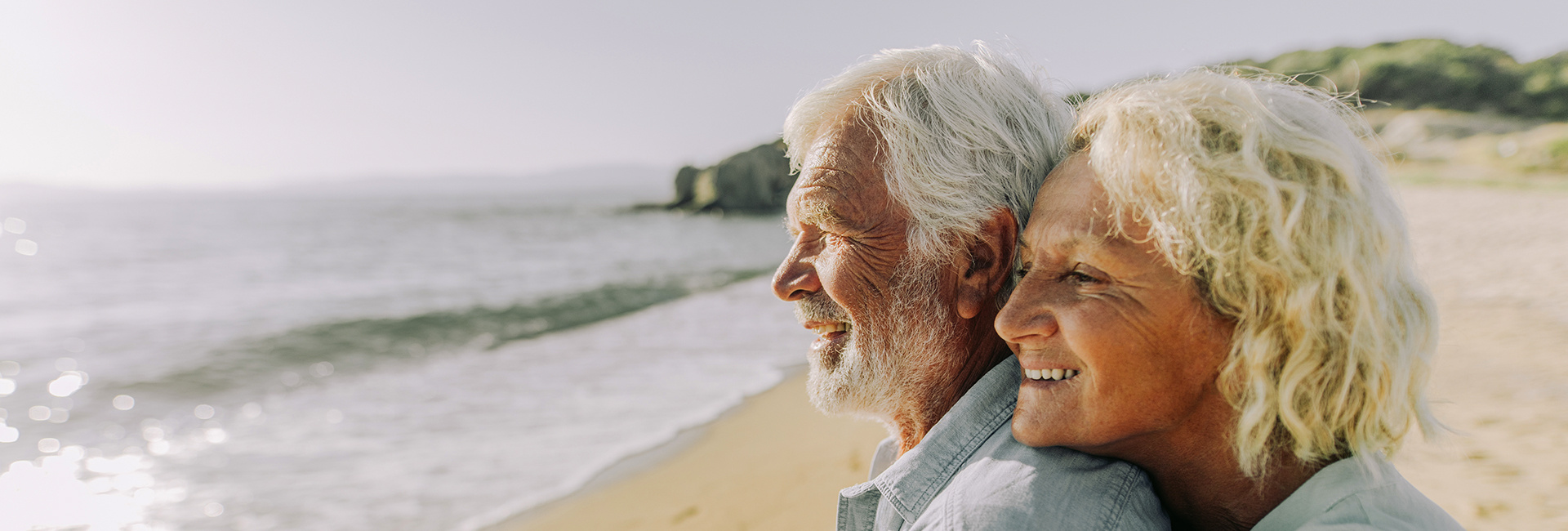 Older couple looking at the sea from the beach. 