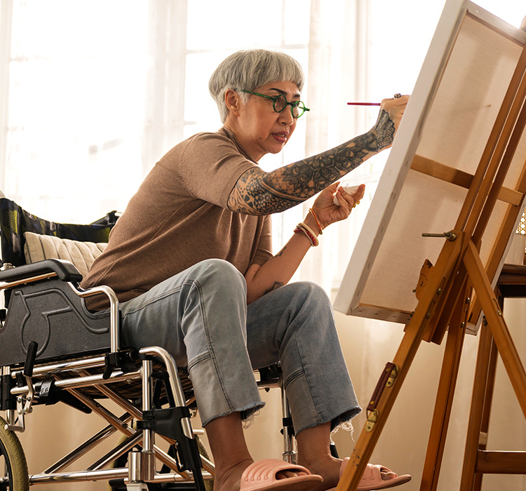 Woman paints on canvas from a wheelchair. 