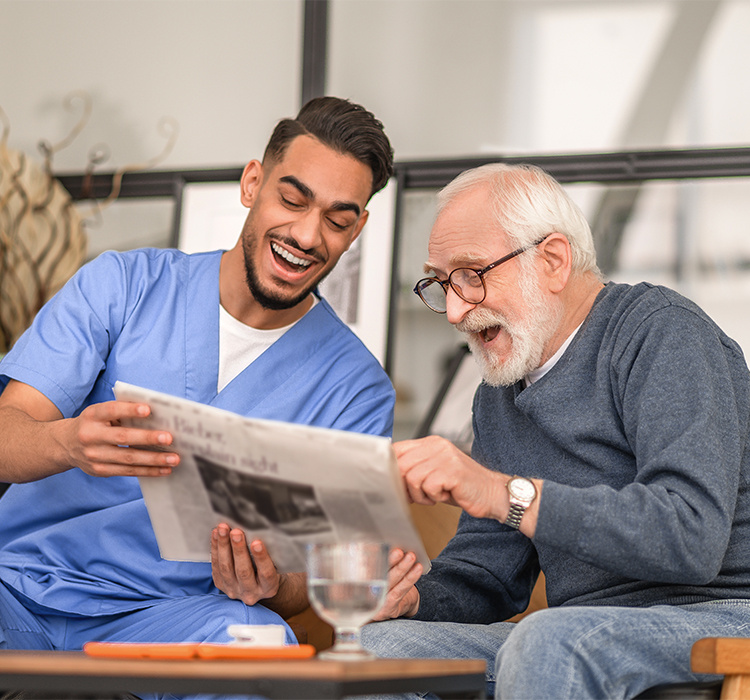 Ebenezer resident and his aid laugh at a newspaper story. 