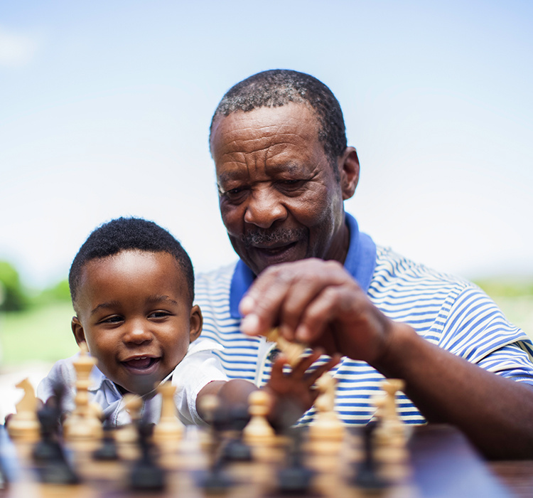 Older man explains chess to his grandson. 