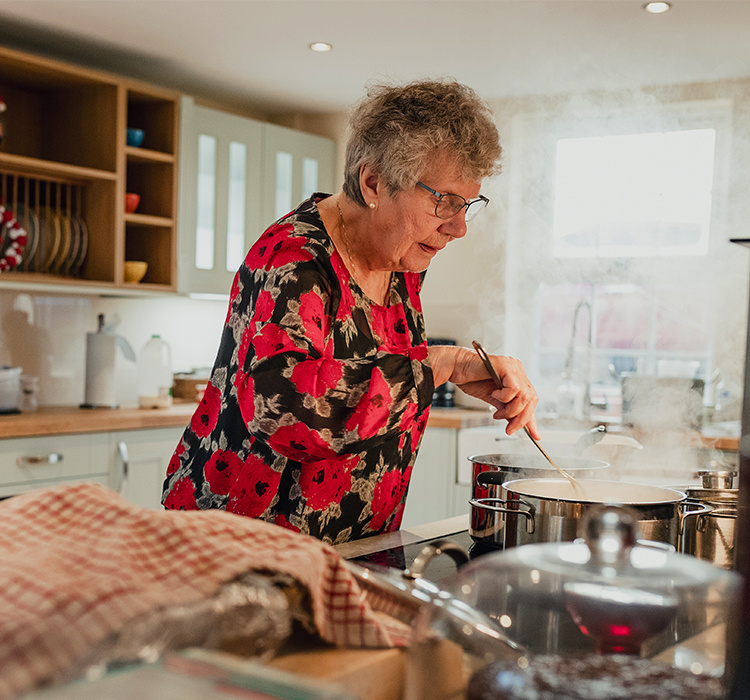 Older woman cooks dinner in her apartment. 