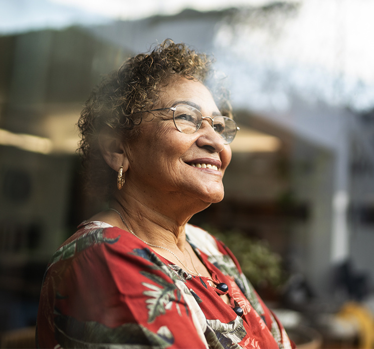 Older woman looking out the window and smiling. 