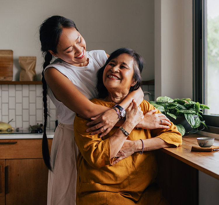 Daughter embracing her mother in the kitchen. 