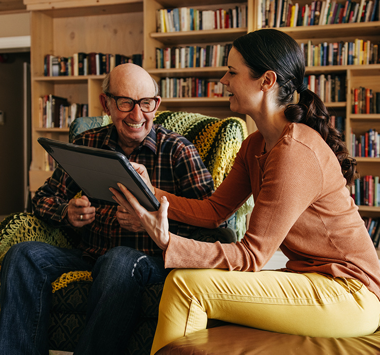 Aid helps a senior with his iPad tablet. 