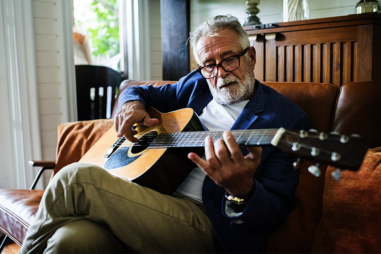 Senior man learning to play guitar.  